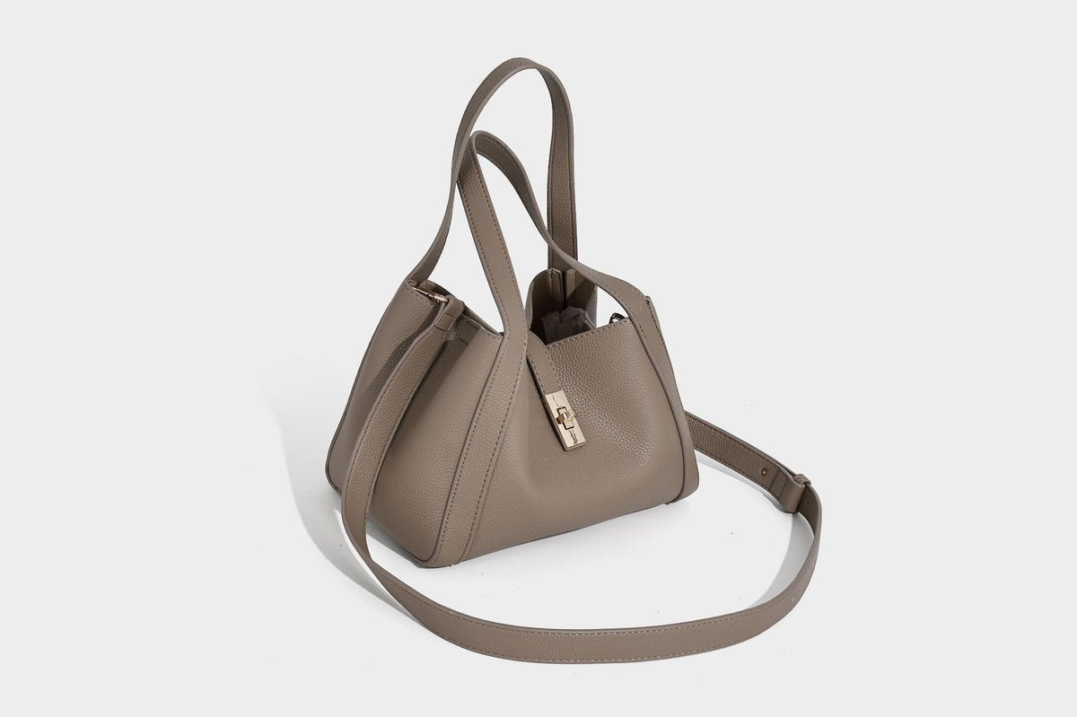 Structured trapezoid tote bag in taupe pebbled leather-look finish with gold-tone turn-lock hardware, dual top handles, and