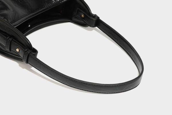 Strukturierte, trapezförmige Schultertasche aus glänzender, geknautscht wirkender Lederoptik mit goldfarbenen Beschlägen auf der Vorderseite und langem, verstellbarem