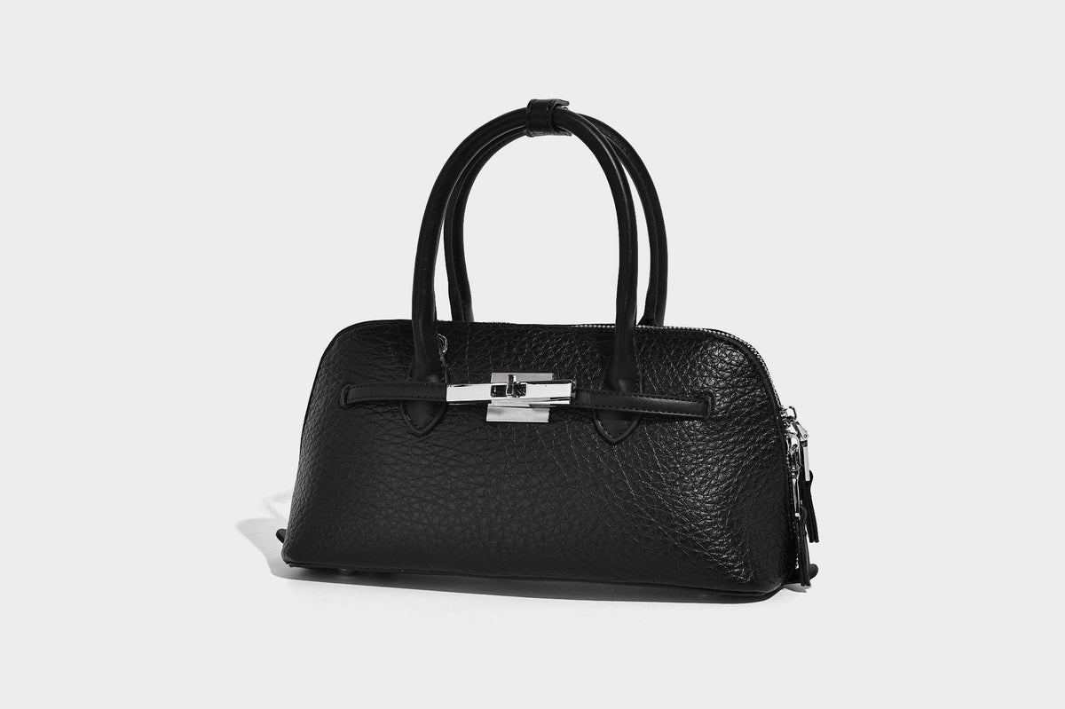 Small structured shell-silhouette top-handle bag with pebbled leather-look finish, silver-tone turn-lock hardware, and