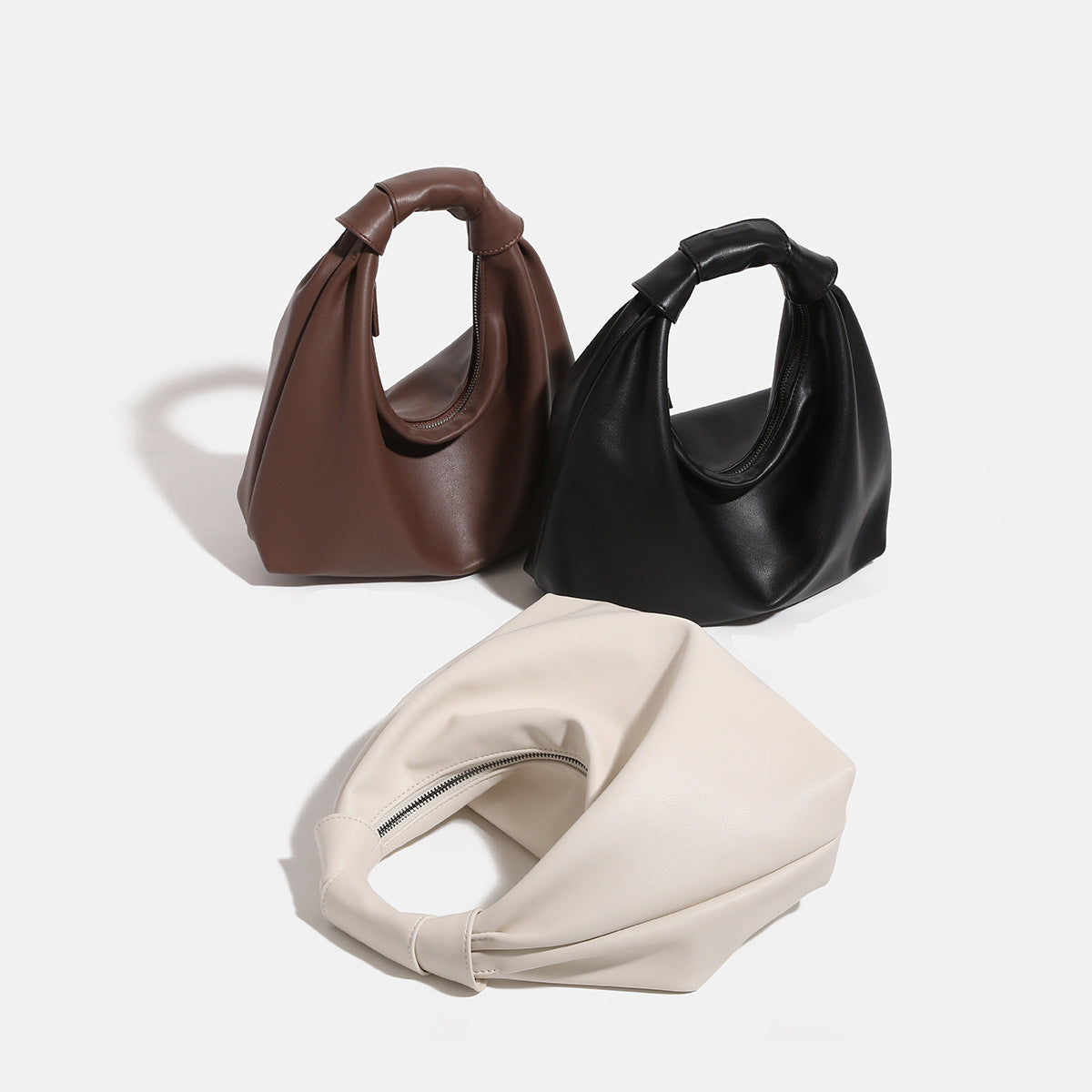 Slouchy leather-look hobo bag with knotted loop handle and top zipper closure, front view