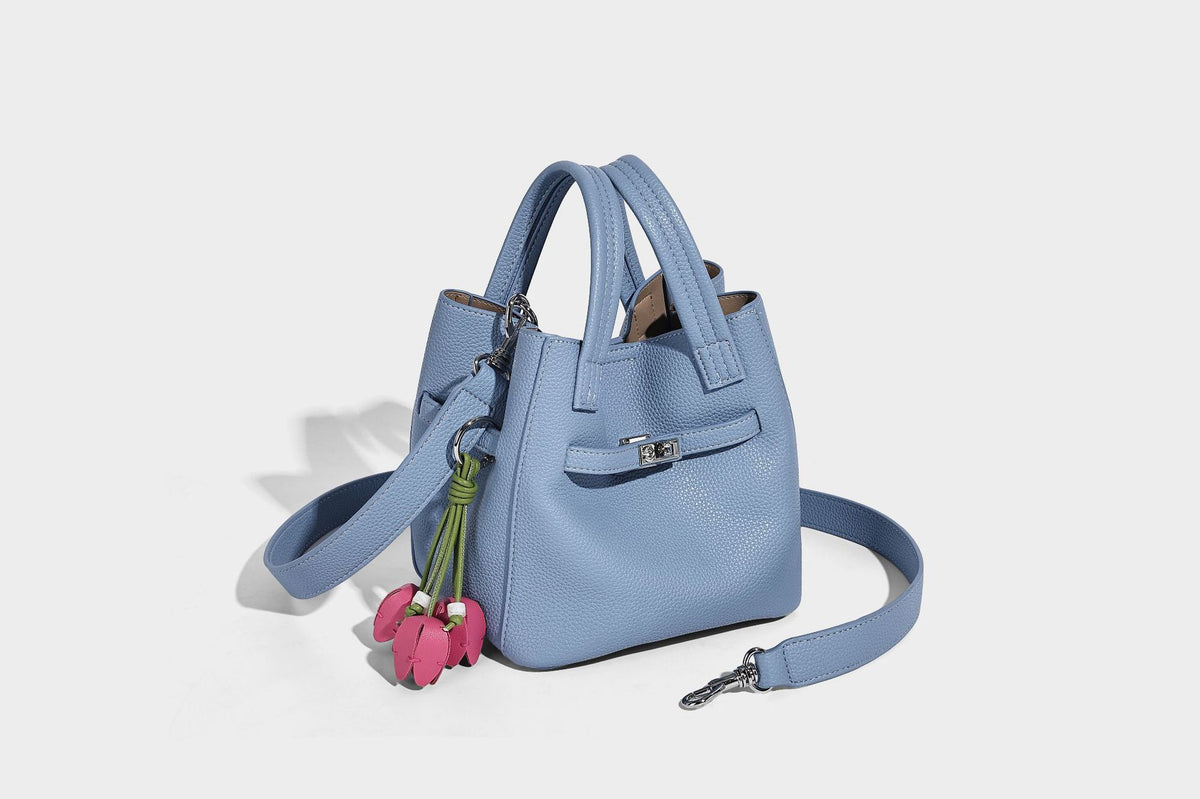 Small structured pebbled bucket tote bag with dual top handles, silver turn-lock front pocket, and detachable shoulder strap