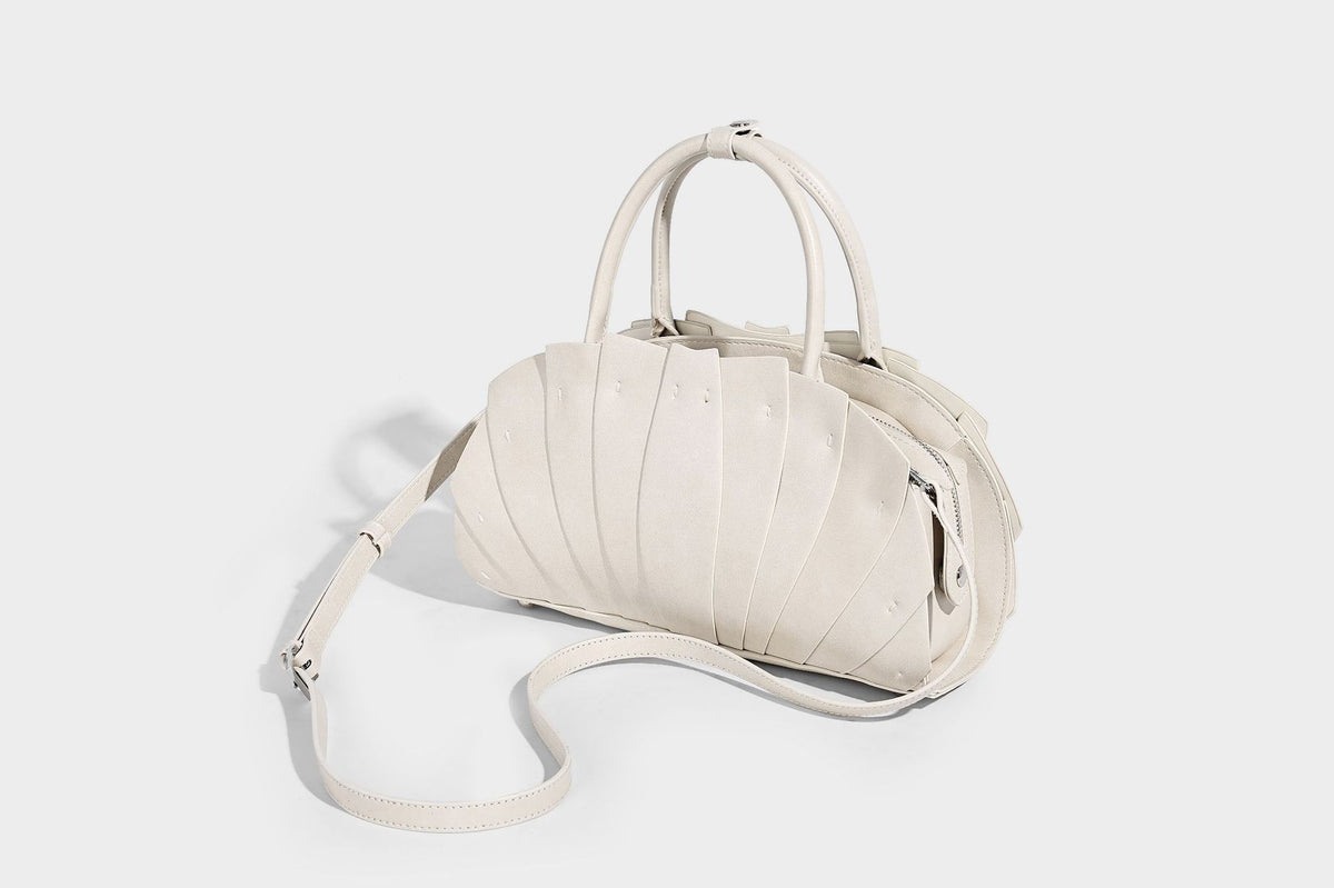 Structured dome satchel with fan-pleated leather-look exterior, dual top handles, and detachable shoulder strap, detail view