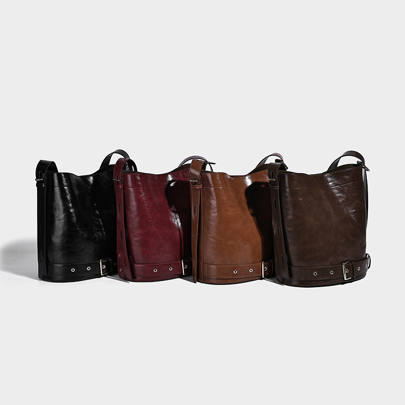 Glossy leather-look bucket bag with wraparound belt strap, silver-tone grommets, and adjustable shoulder strap, detail view 2