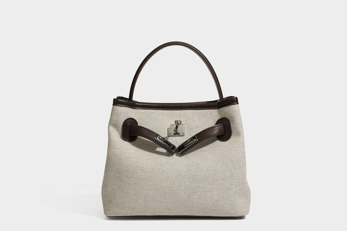 Small structured beige canvas top-handle bag with dark brown leather-look trim, silver turn-lock hardware, and detachable