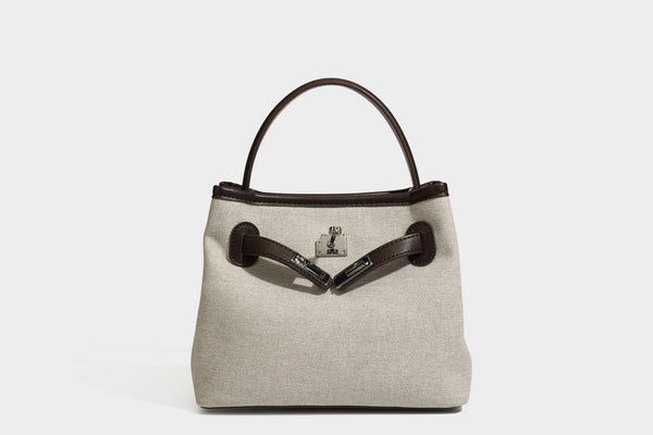 Small structured beige canvas top-handle bag with dark brown leather-look trim, silver turn-lock hardware, and detachable