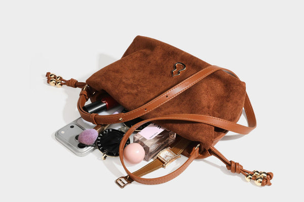 Suede-look drawstring shoulder bag in brown with smooth trim, knotted bead drawstring closure, slim adjustable strap, and