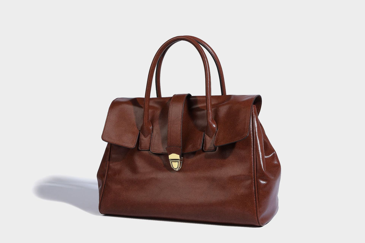 Strukturierte Henkeltasche in glänzender Lederoptik mit Überschlagverschluss, mittigem Riemen, goldfarbenem Drehverschluss und zwei Henkeln