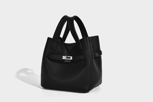 Small structured pebbled bucket tote bag with dual top handles, silver turn-lock front pocket, and detachable shoulder strap