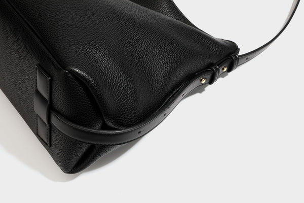 Slouchy hobo shoulder bag with pebbled leather-look finish, zip-top closure, gold-tone hardware, and hanging bead charm