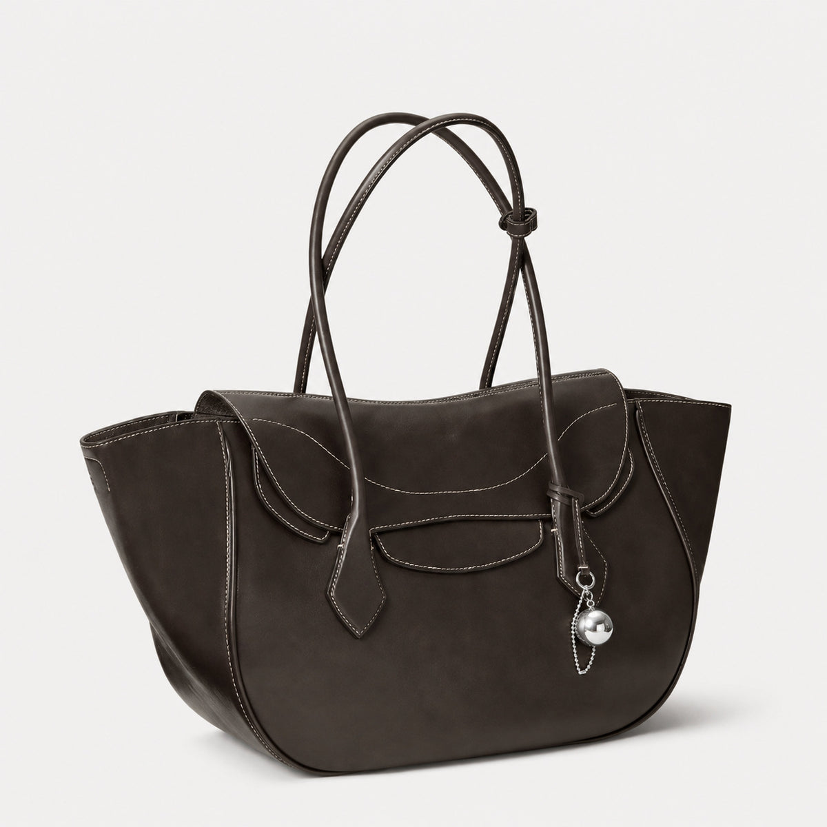 Large winged leather-look tote bag with single arched handle, stitched flap-front panel, and silver ball charm in cognac