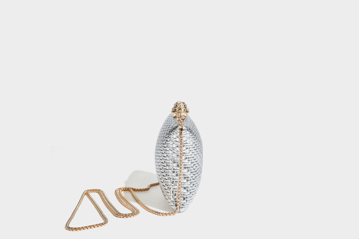 Small structured rectangular metallic woven-texture clutch bag with jeweled knob clasp and gold-tone chain strap, detail view