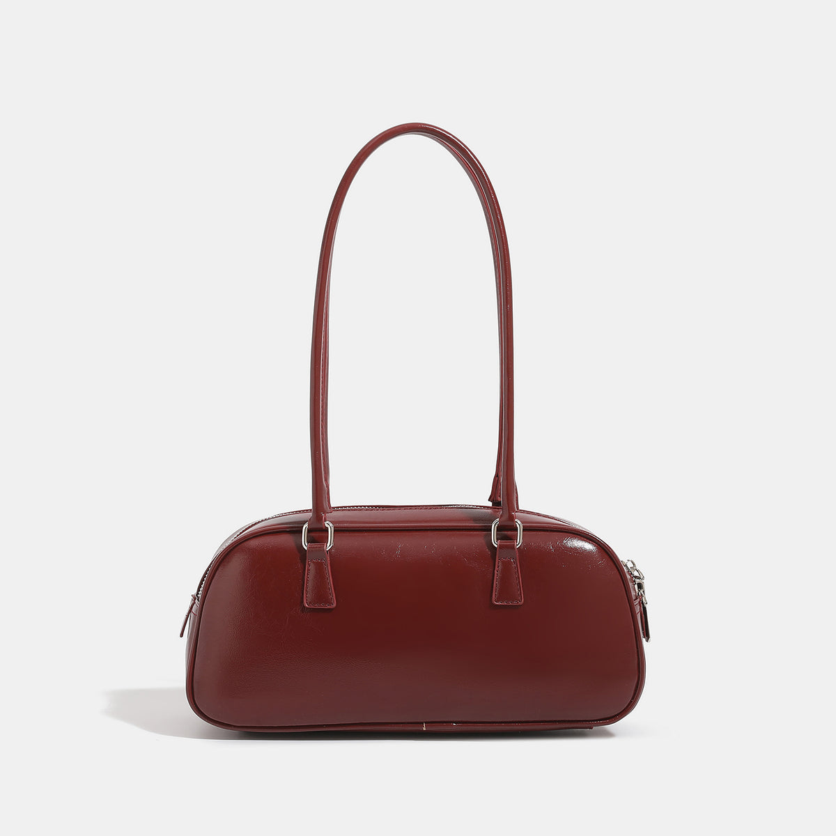 Rounded baguette shoulder bag with glossy leather-look finish, double-pull zip top, dual top handles, and silver-tone, detail