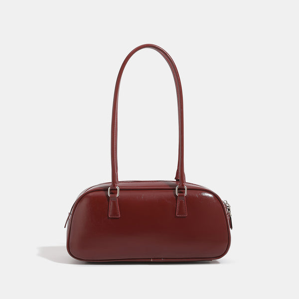 Rounded baguette shoulder bag with glossy leather-look finish, double-pull zip top, dual top handles, and silver-tone, detail