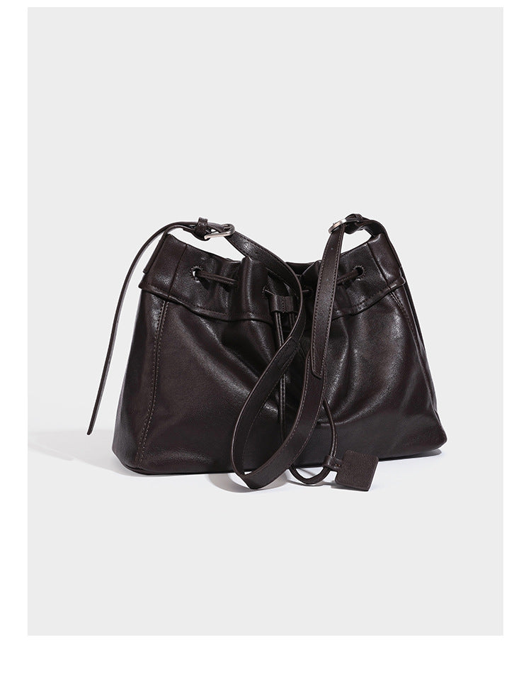 Slouchy drawstring bucket bag in dark brown leather-look finish with long adjustable shoulder strap and gathered tie closure