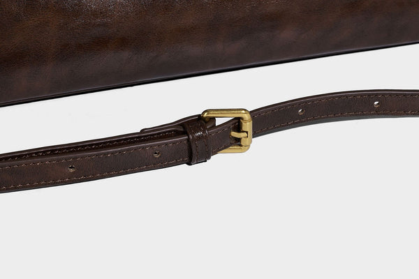 Strukturierte dunkelbraune Henkeltasche mit Öl-Wachs-Finish, vorderer Gürtelschnalle, goldfarbenen Beschlägen und zwei Tragegriffen, Detailansicht