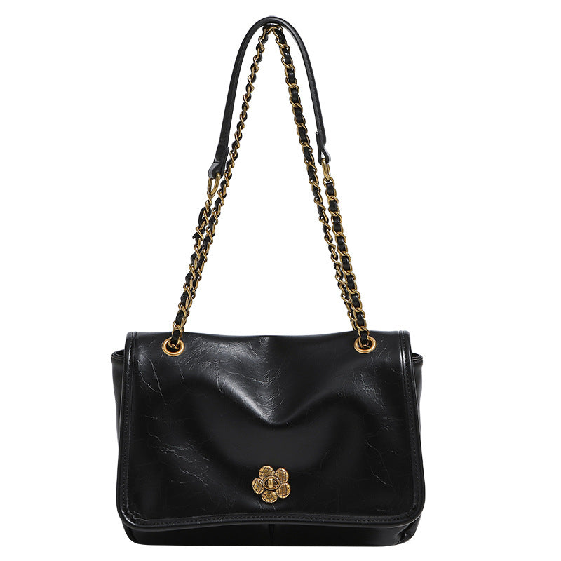 Structured flap shoulder bag with antique gold-tone chain strap and flower turn-lock clasp in crinkled leather-look finish