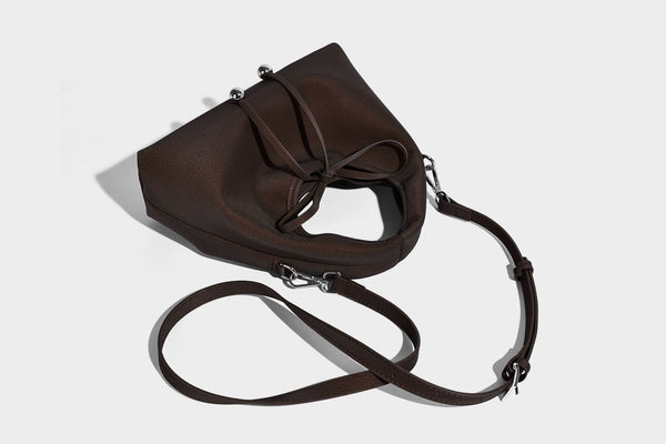 Pebbled matte trapezoid top-handle bag with drawstring bow closure, bead-tipped cords, silver-tone hardware, and detachable