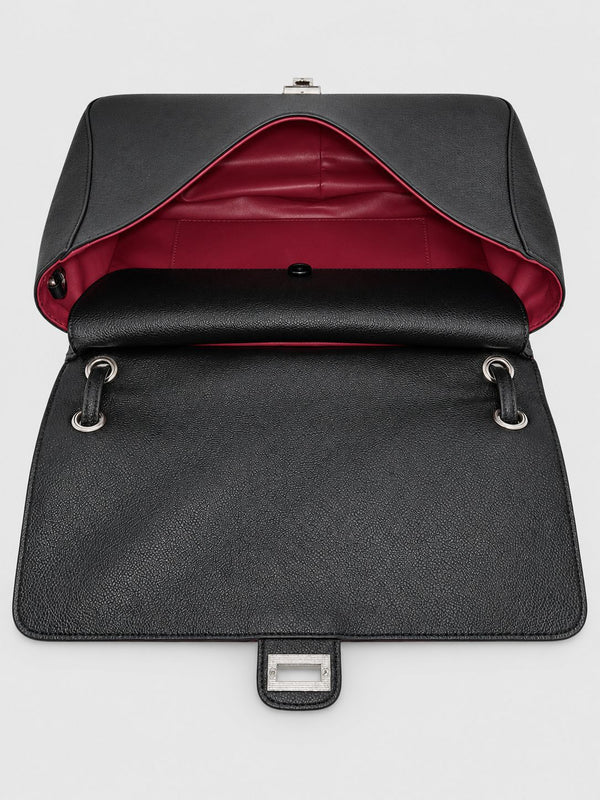 Structured black flap shoulder bag with pebbled texture, silver-tone turn-lock closure, and adjustable single shoulder strap