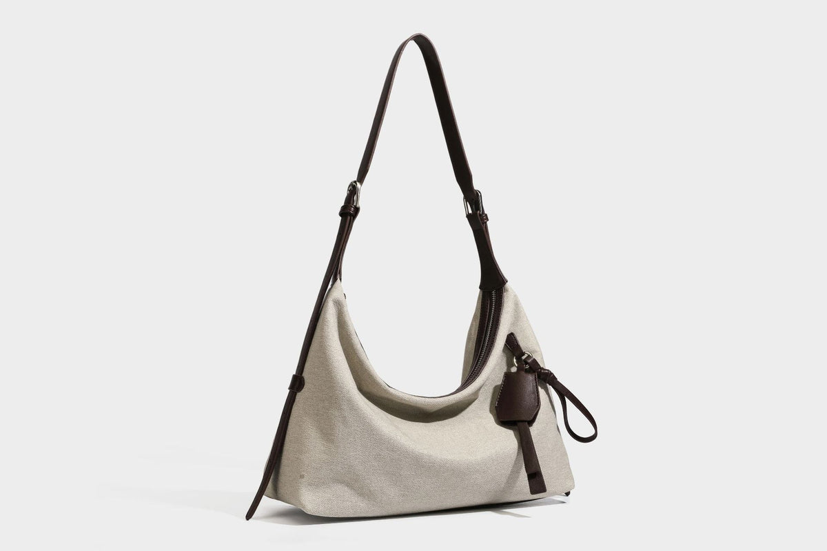 Lässige Hobo-Schultertasche aus haferfarbenem Canvas mit dunkelbraunen Besätzen in Lederoptik, silberfarbenem Reißverschluss und langem, verstellbarem