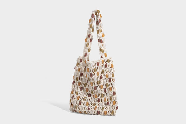 Cream macramé open-weave tote bag with multicolor amber olive and translucent bead accents and woven shoulder straps, detail