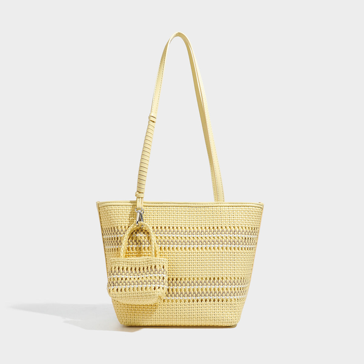 Large structured woven tote bag with striped basket-weave finish, long shoulder straps, and detachable mini pouch charm