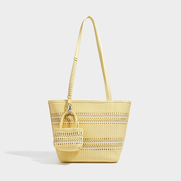 Large structured woven tote bag with striped basket-weave finish, long shoulder straps, and detachable mini pouch charm