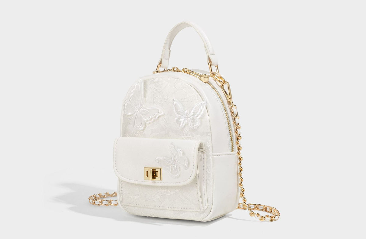 Structured mini backpack handbag with butterfly embroidery, gold-tone chain strap, and turn-lock front flap pocket, detail