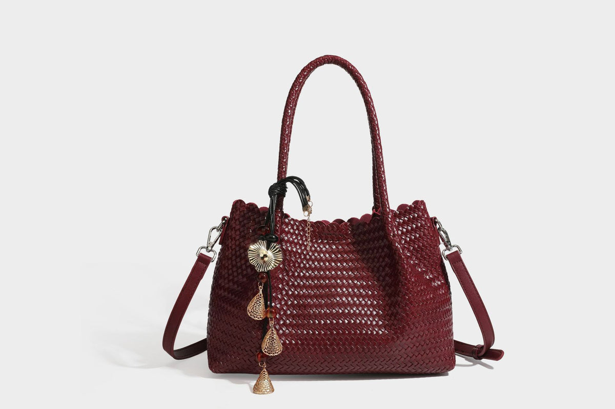 Strukturierter, glänzend geflochtener Shopper mit Muschelkantenabschluss am oberen Rand, geflochtenen Tragegriffen, abnehmbarem Crossbody-Riemen und Perlenquaste