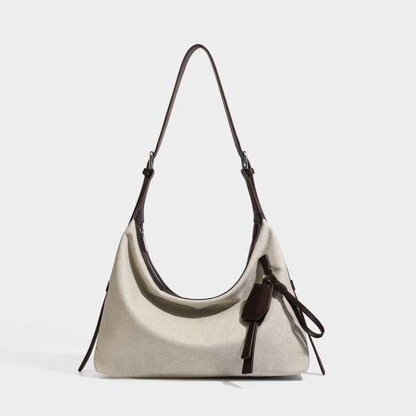 Weich fallende Hobo-Schultertasche aus haferfarbenem Canvas mit dunkelbraunem Besatz in Lederoptik, silberfarbenem Reißverschluss und langem, verstellbarem