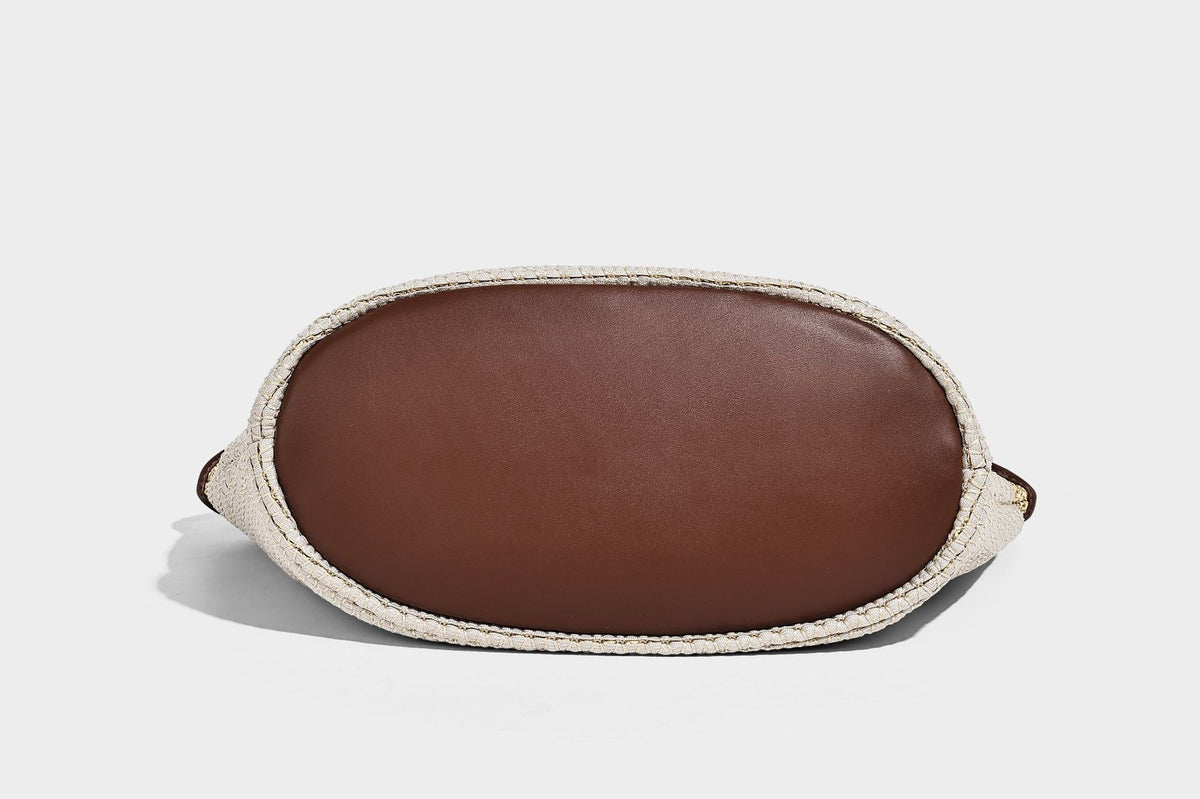 Two-tone beige and cream woven straw hobo shoulder bag with brown leather-look trim, long shoulder strap, and tassel-bead