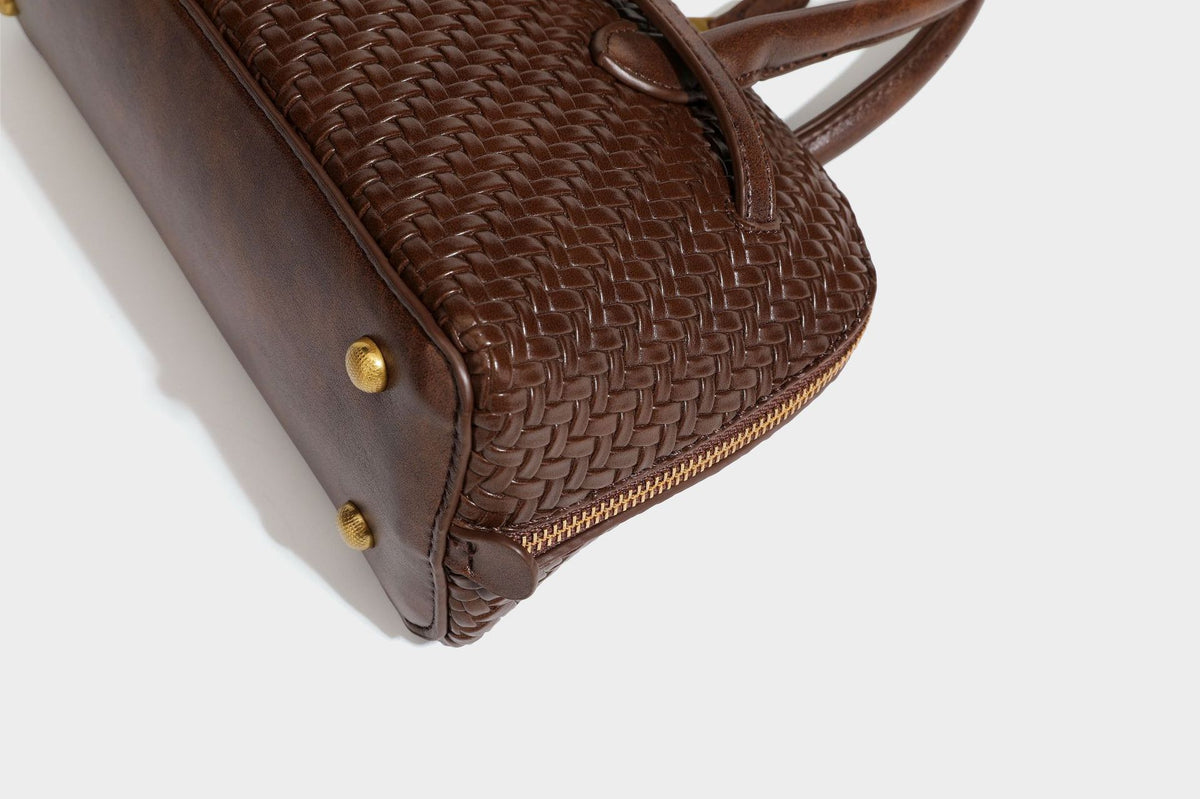 Structured woven-embossed leather-look satchel with dual rolled top handles, gold-tone turn-lock closure, and detachable