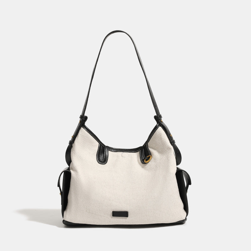Off-white canvas hobo shoulder bag with black leather-look trim, gold-tone ring hardware, top zip closure, side pockets, and