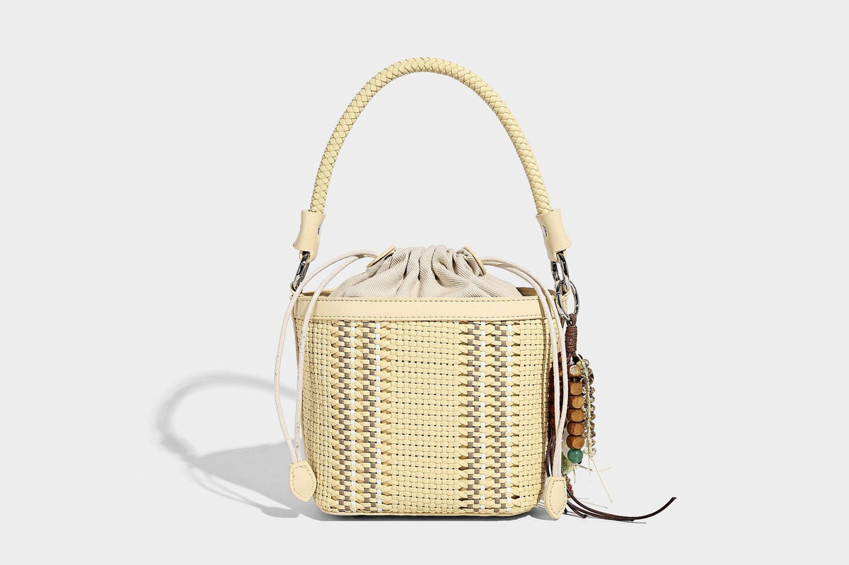 Small woven bucket bag with drawstring top, braided handle, detachable crossbody strap, and silver-tone ring hardware, detail