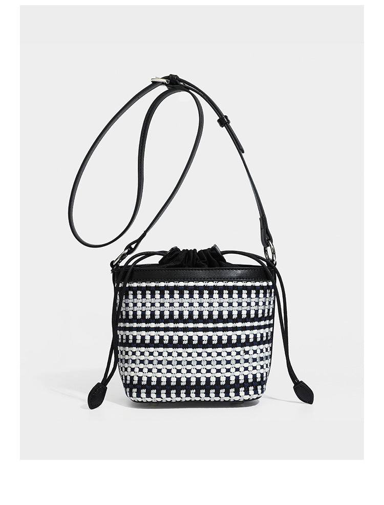 Small structured woven checker bucket bag with braided top handle, drawstring closure, and silver-tone hardware in black