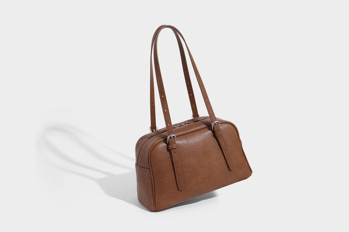 Structured dome-shaped shoulder bag with leather-look finish, top zipper closure, dual adjustable slim straps, and, detail