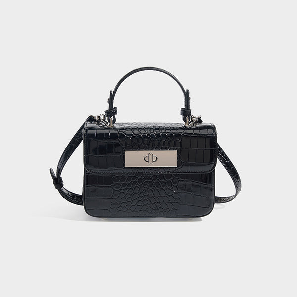 Small structured rectangular satchel with glossy crocodile-embossed finish, arched top handle, front flap, and silver-tone