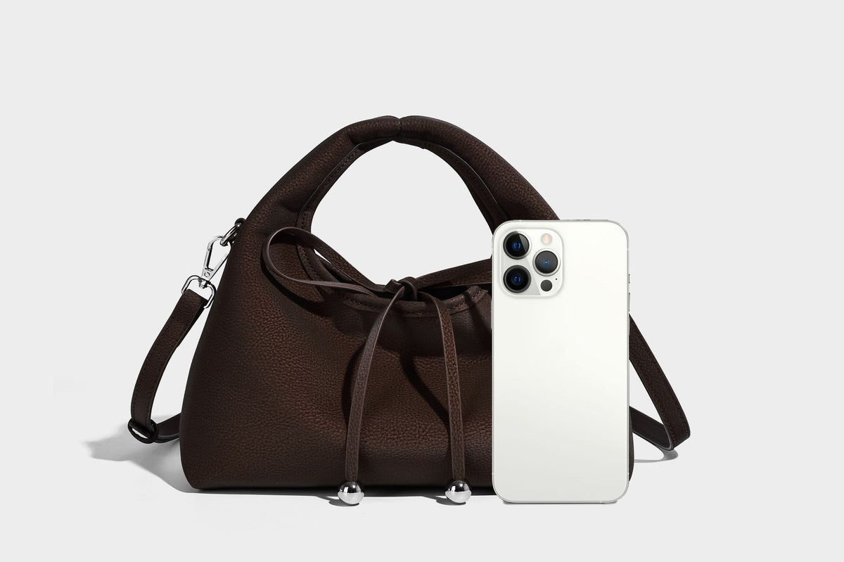 Pebbled matte trapezoid top-handle bag with drawstring bow closure, bead-tipped cords, silver-tone hardware, and detachable