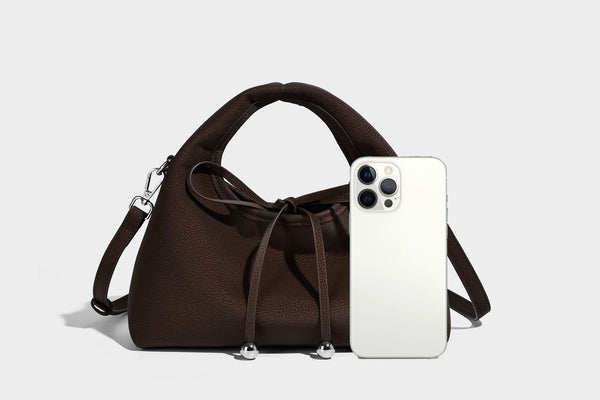 Pebbled matte trapezoid top-handle bag with drawstring bow closure, bead-tipped cords, silver-tone hardware, and detachable