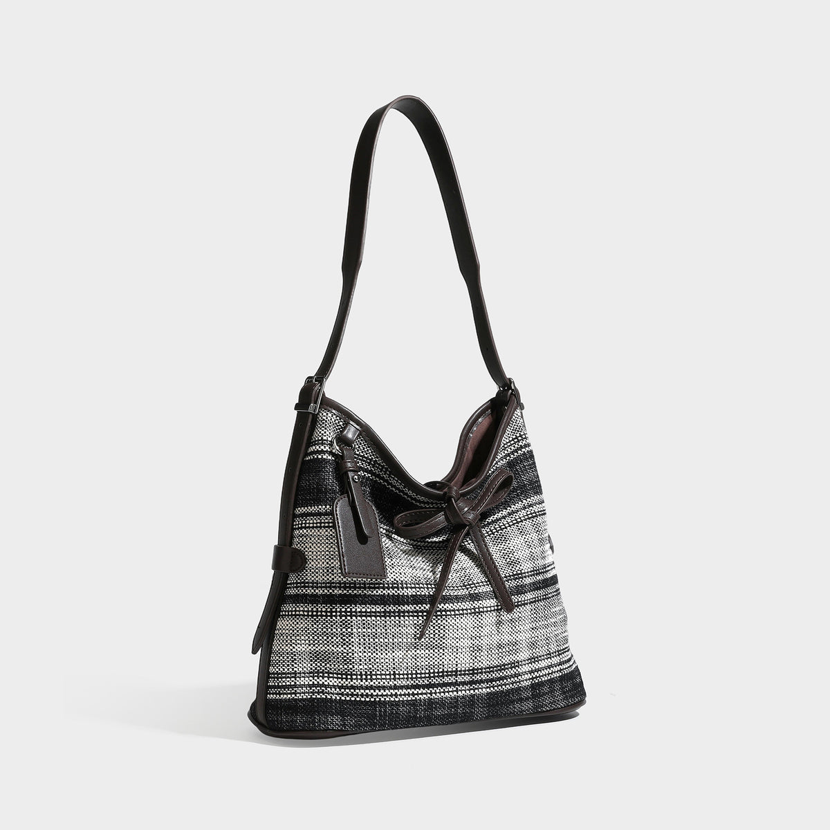 Black-and-white woven plaid hobo shoulder bag with dark brown leather-look trim, drawstring tie closure, and long adjustable