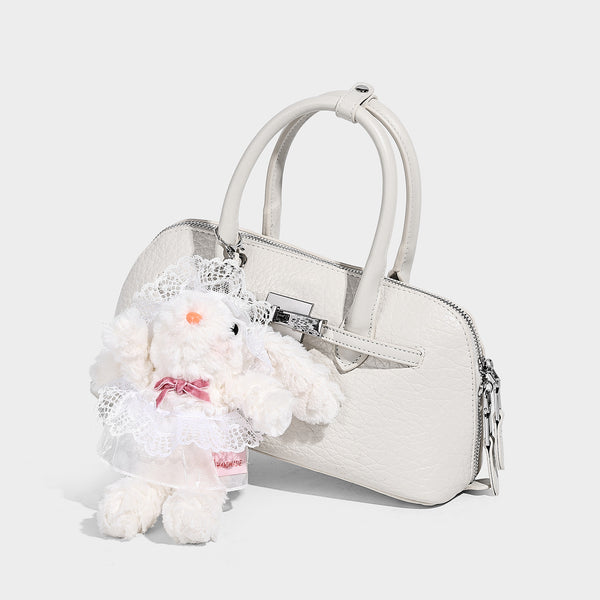 Small structured shell-silhouette top-handle bag with pebbled leather-look finish, silver-tone turn-lock hardware, and