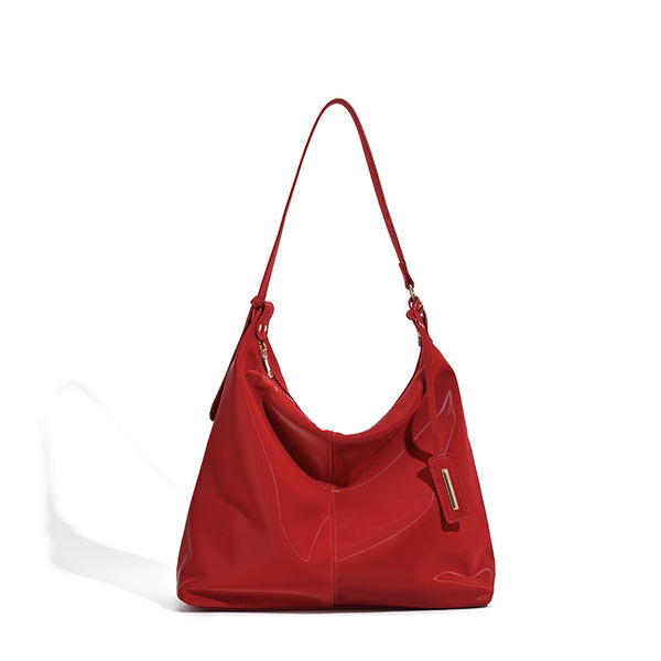Large red glossy leather-look slouchy hobo shoulder tote bag with zip-top closure and gold-tone hardware, detail view 5