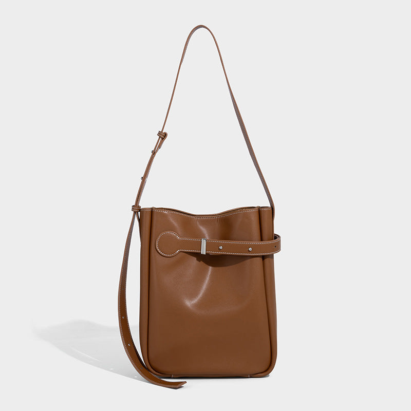 Structured dark brown leather-look bucket bag with white contrast stitching, front wraparound belt buckle strap, and long