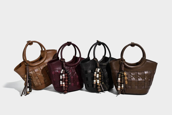 Small woven-panel bucket bag with circular ring handles, beaded tassel charm, and detachable crossbody strap in brown, detail