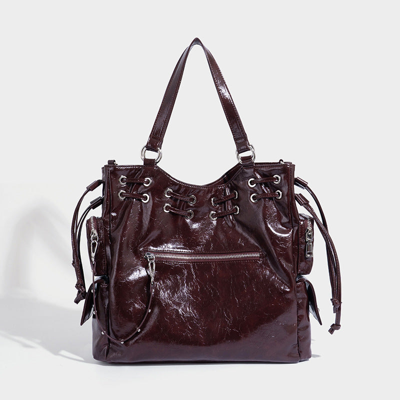Glossy crinkled leather-look tote bag with silver grommet lace-up front detail, dual top handles, and detachable shoulder