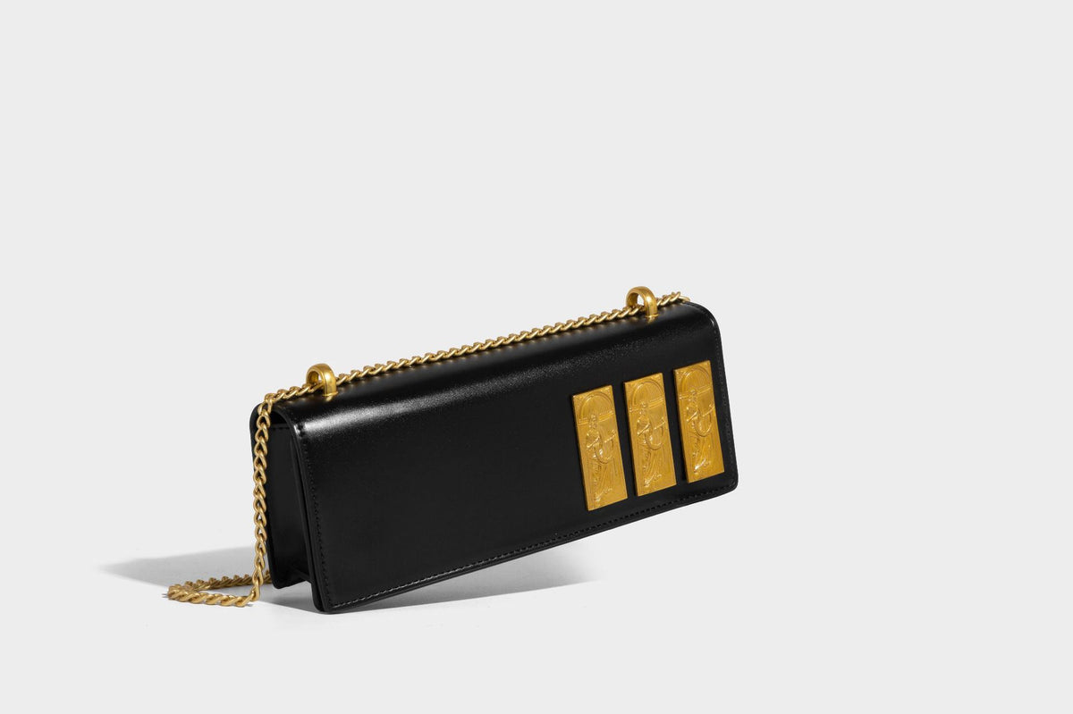 Structured rectangular crossbody bag with glossy finish, three vertical gold-tone embossed plaques, and gold chain strap