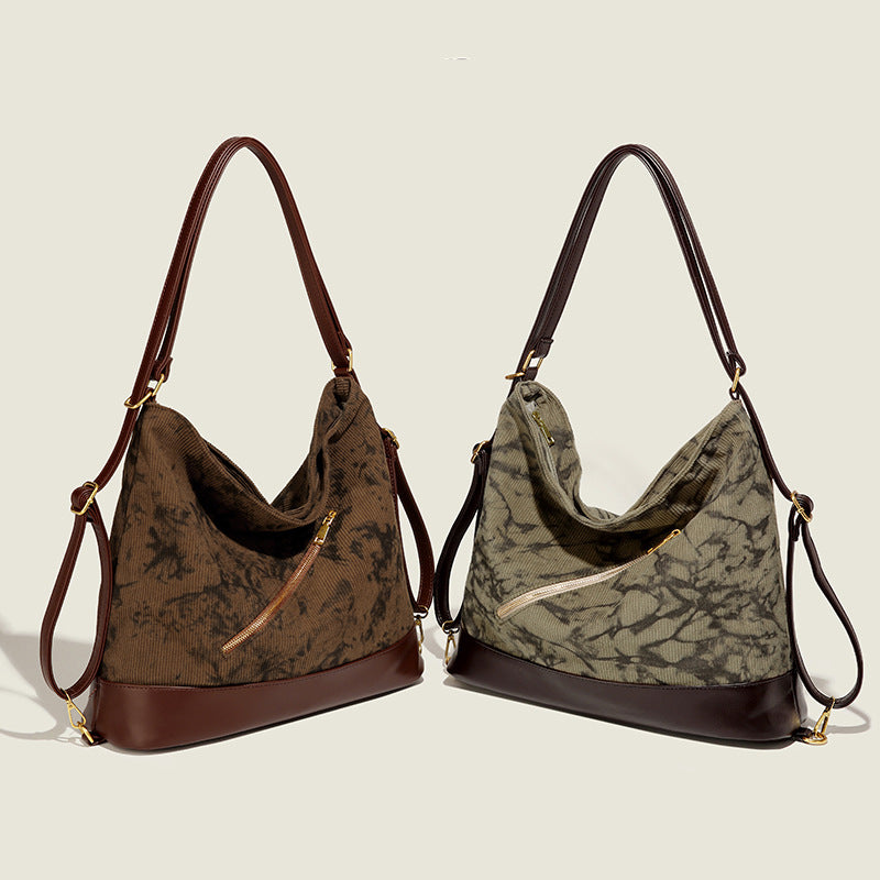 Große Hobo-Tasche aus Cord mit Ink-Wash-Print, dunkelbrauner Bodenbesatz in Lederoptik, diagonalem Reißverschlussfach vorne und goldfarbenem