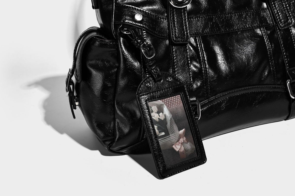 Glossy structured black tote shoulder bag with silver buckle hardware, zip pockets, dual top handles, and detachable, detail