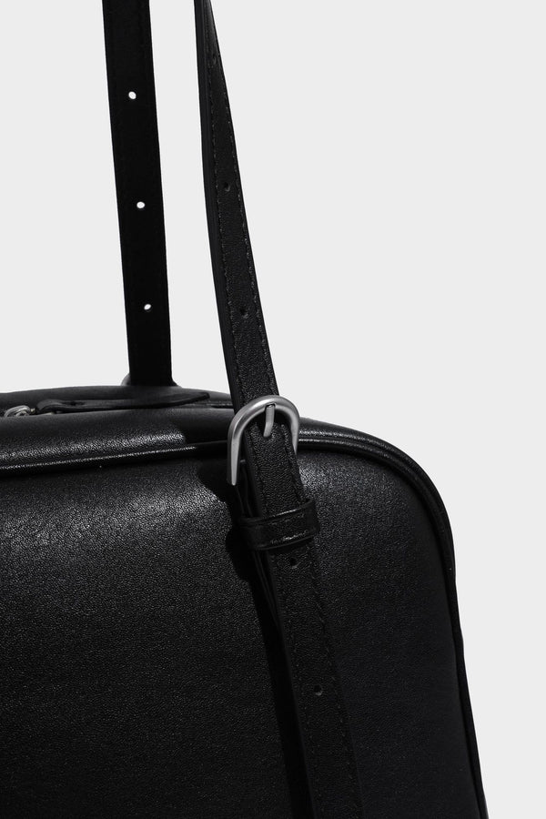 Structured dome-shaped shoulder bag with leather-look finish, top zipper closure, dual adjustable slim straps, and, detail