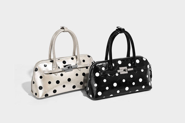 Glossy structured polka-dot satchel bag with dual top handles, silver turn-lock hardware, and detachable shoulder strap