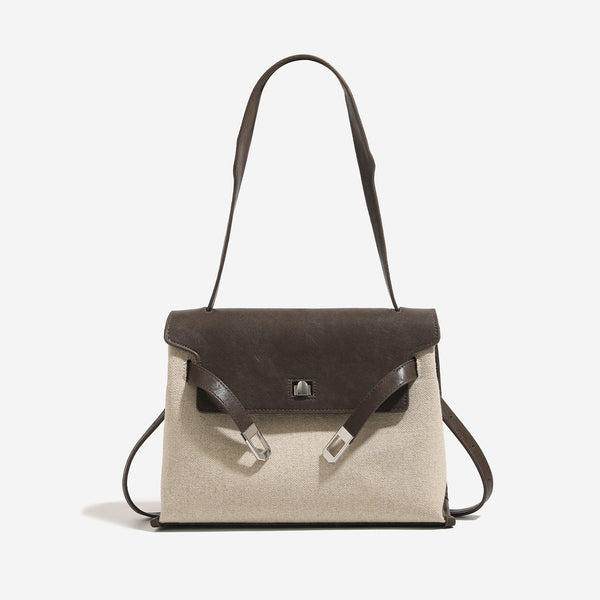 Structured trapezoidal flap satchel bag with silver-tone turn-lock clasp, decorative front strap tabs, gusseted sides, and